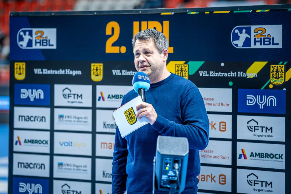 Andreas Klement als Handball Kommentator bei einem Spiel der 2. Handball Bundesliga für Eintracht Hagen mit Mikrofon am Spielfeldrand